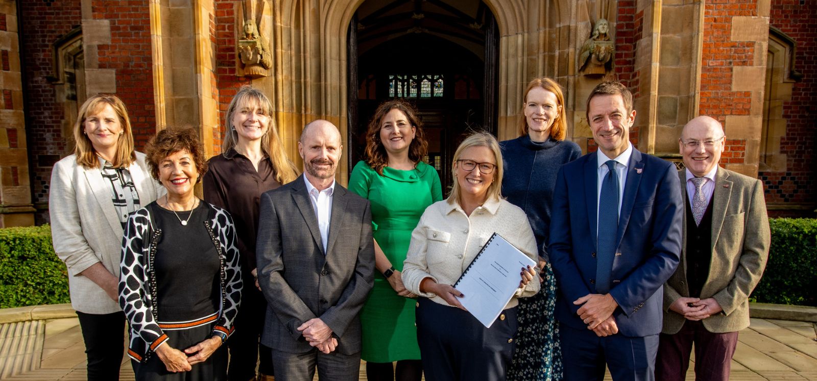 Representatives from Queen's and the Belfast Trust pictured in front of the Lanyon building on a sunny day